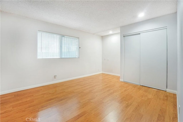 unfurnished bedroom with light hardwood / wood-style floors, a textured ceiling, and a closet