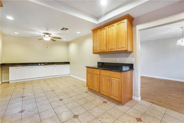 kitchen with ceiling fan, dark stone counters, and light tile patterned floors