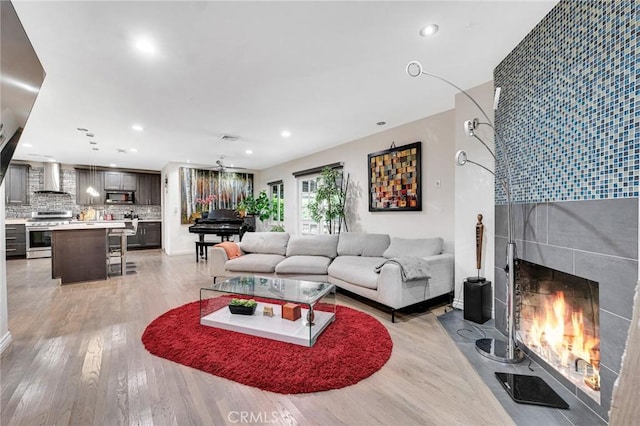 living room with ceiling fan, a fireplace, and light hardwood / wood-style flooring