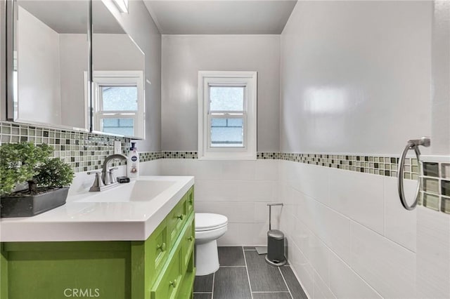 bathroom with tile walls, toilet, and vanity