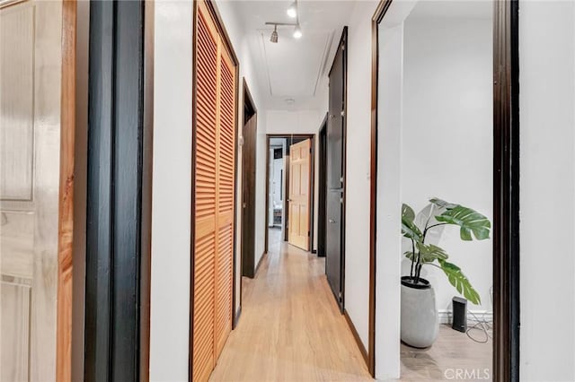 hallway with rail lighting and light hardwood / wood-style flooring