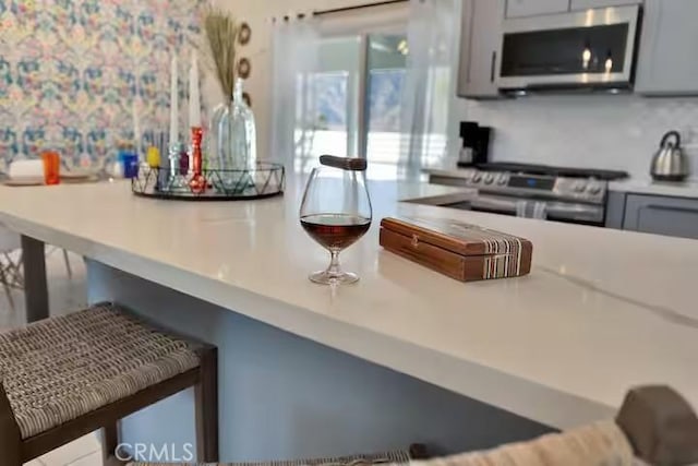 kitchen featuring appliances with stainless steel finishes, decorative backsplash, and gray cabinets