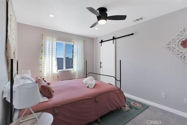 bedroom featuring ceiling fan, a barn door, and carpet floors