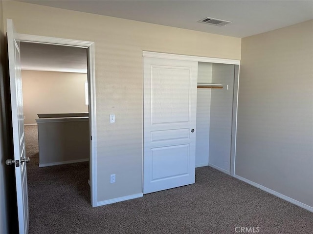 unfurnished bedroom featuring a closet and dark carpet