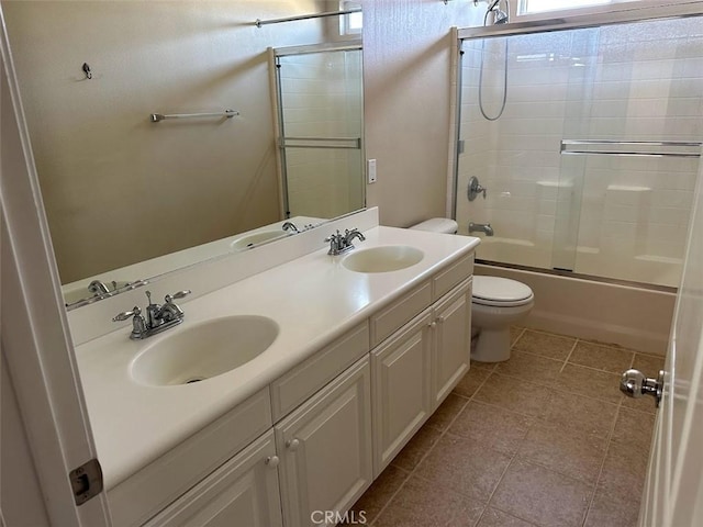 full bathroom with tile patterned floors, bath / shower combo with glass door, toilet, and vanity