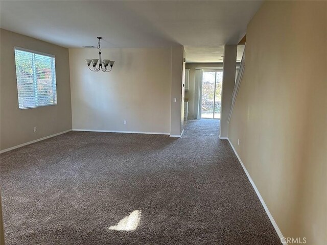 carpeted spare room with an inviting chandelier