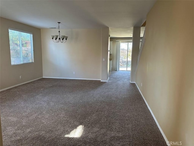 empty room featuring carpet flooring and an inviting chandelier