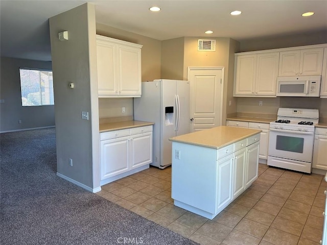 kitchen with light tile patterned flooring, white appliances, white cabinetry, and a kitchen island