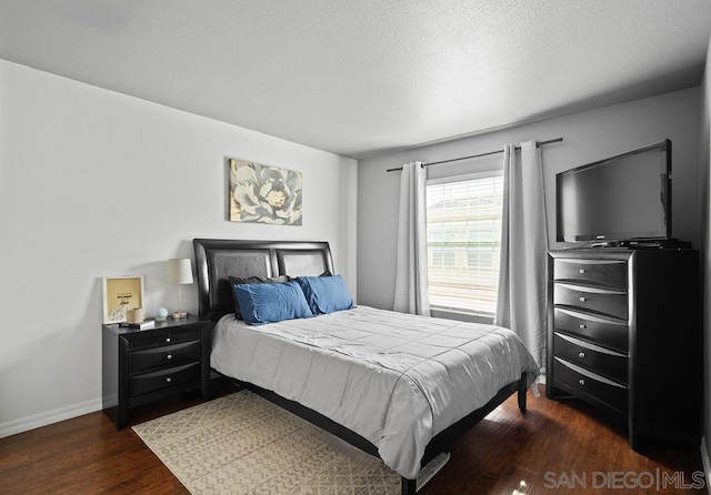 bedroom with dark hardwood / wood-style floors and a textured ceiling