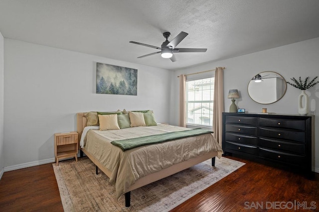 bedroom with a textured ceiling, ceiling fan, and dark hardwood / wood-style flooring