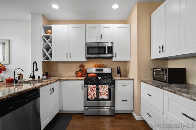 kitchen featuring stainless steel appliances, dark stone countertops, white cabinets, and sink