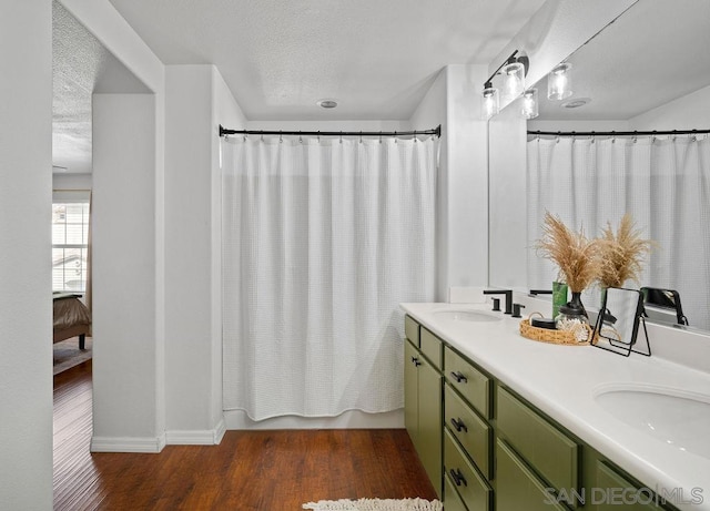 bathroom with a textured ceiling, hardwood / wood-style flooring, vanity, and shower / tub combo with curtain