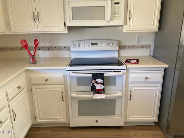 kitchen featuring white cabinetry, wood-type flooring, and white appliances