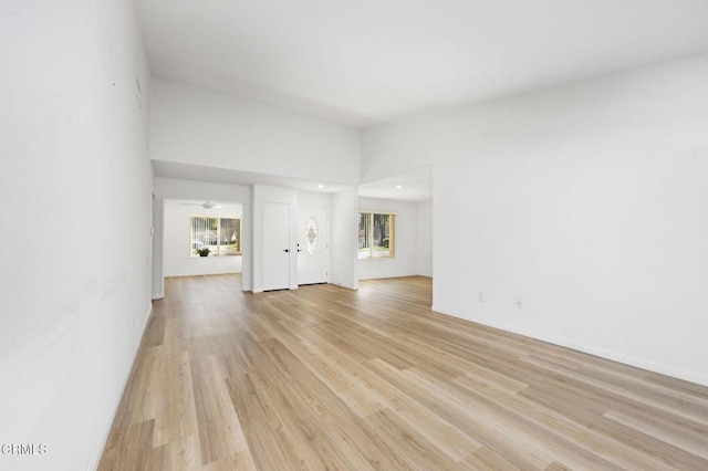 unfurnished living room featuring a towering ceiling and light hardwood / wood-style floors