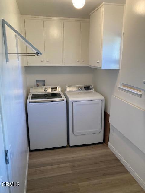 laundry room with washing machine and dryer, cabinets, and dark wood-type flooring