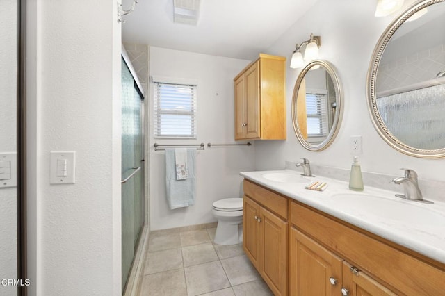 bathroom with toilet, vanity, a shower with door, and tile patterned floors