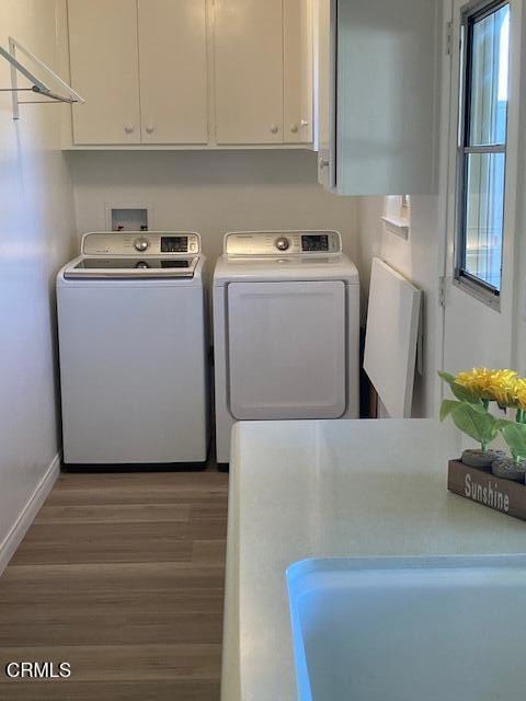 laundry area featuring washer and dryer, cabinets, and hardwood / wood-style floors