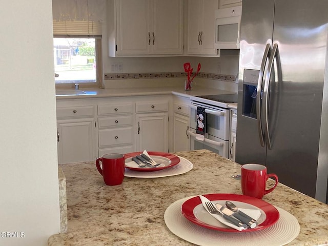 kitchen with white cabinetry, decorative backsplash, light stone counters, and white appliances