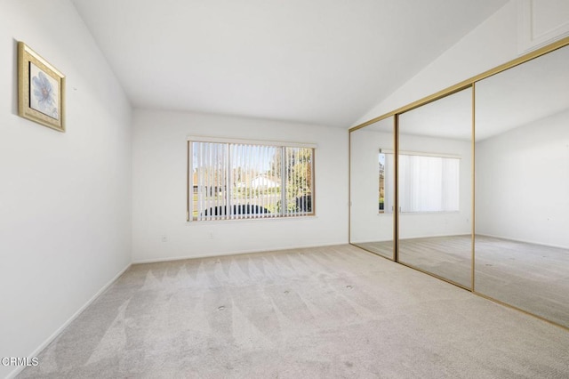 unfurnished bedroom featuring multiple windows, a closet, light carpet, and vaulted ceiling