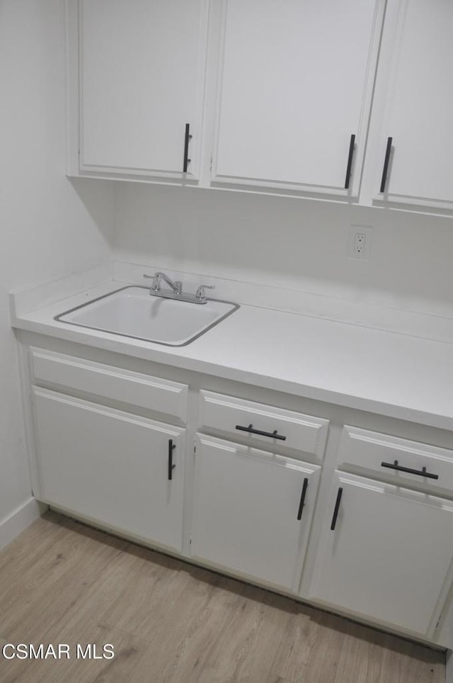 kitchen featuring sink, white cabinets, and light hardwood / wood-style flooring