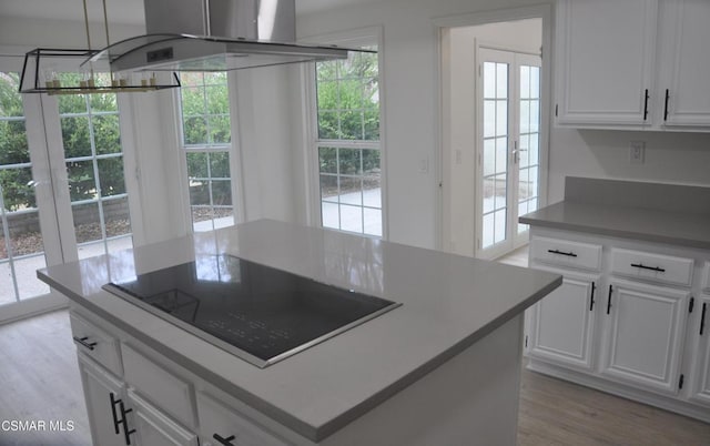 kitchen featuring white cabinetry, a center island, light wood-type flooring, island exhaust hood, and black electric stovetop