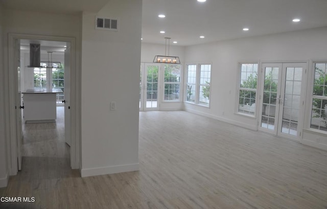 empty room featuring hardwood / wood-style floors, an inviting chandelier, and french doors