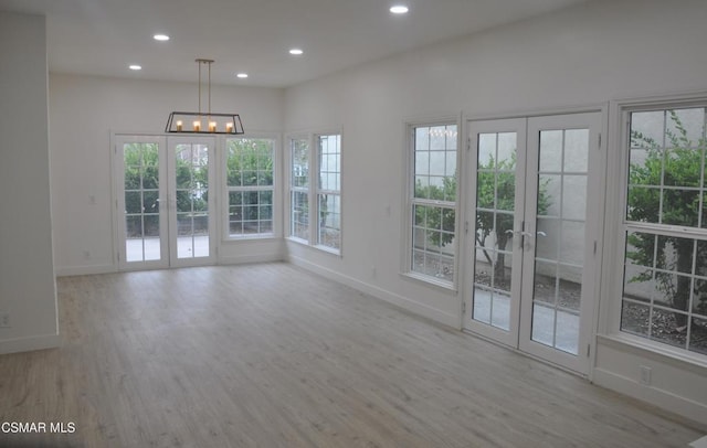 unfurnished dining area featuring french doors and light hardwood / wood-style flooring