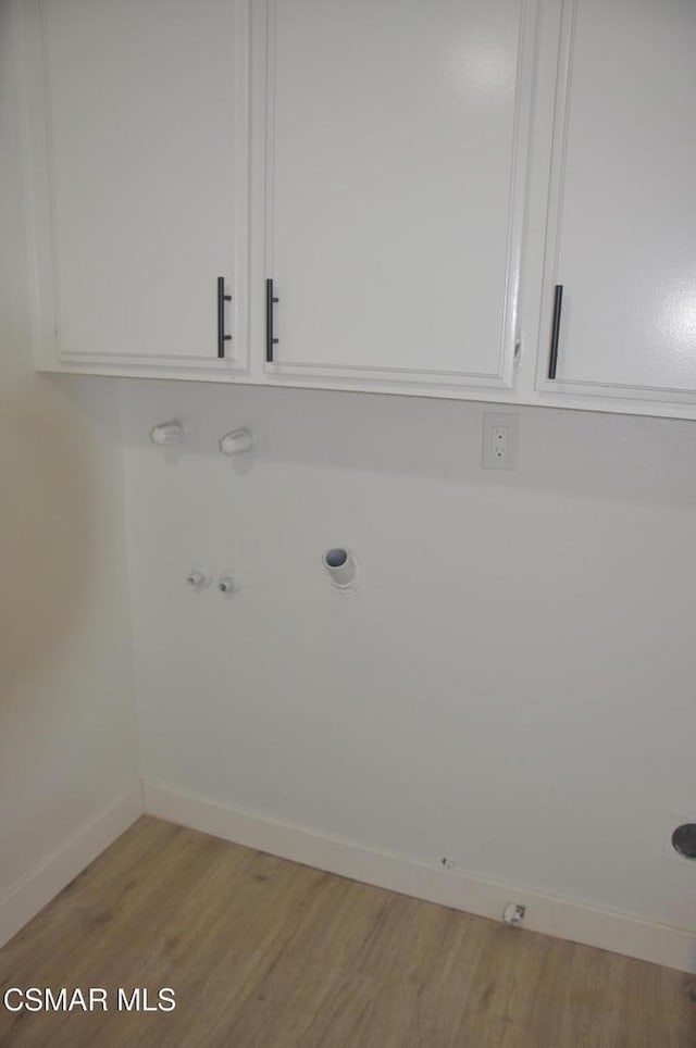 washroom with gas dryer hookup, light hardwood / wood-style floors, and cabinets