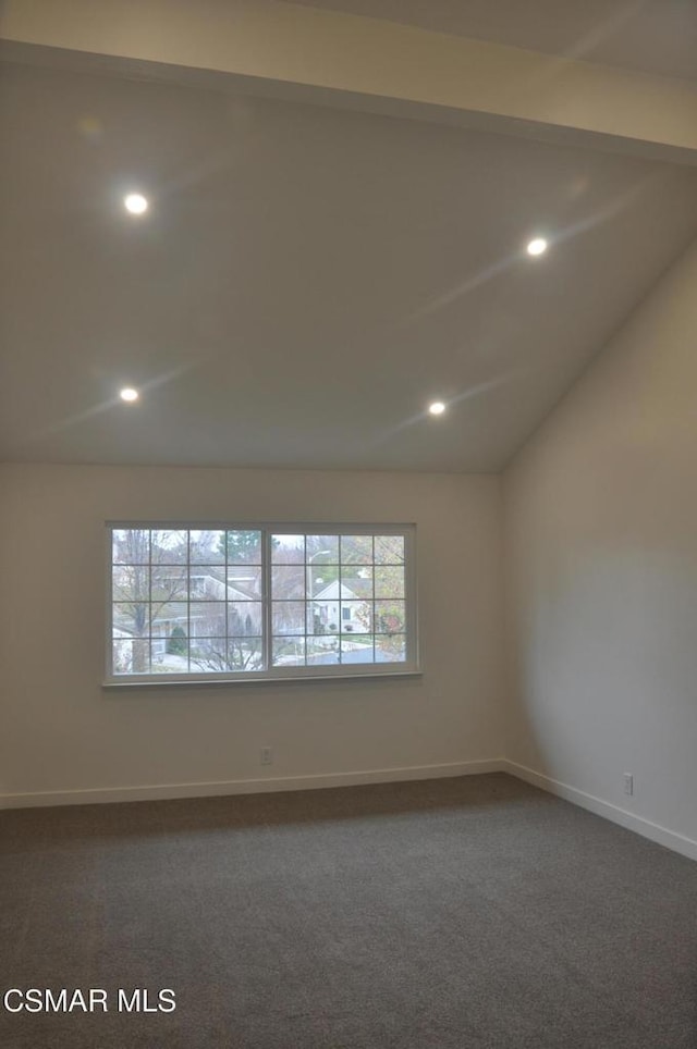 carpeted spare room featuring vaulted ceiling with beams