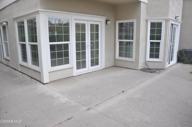 entrance to property with french doors, a patio, and central air condition unit