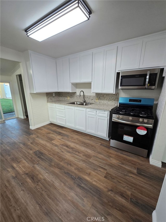 kitchen with white cabinets, appliances with stainless steel finishes, sink, dark hardwood / wood-style floors, and light stone counters