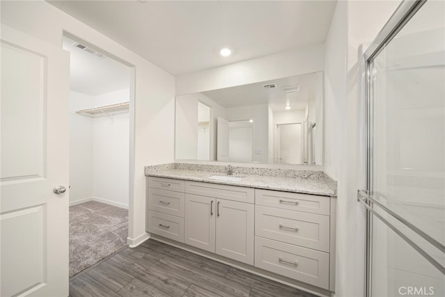 bathroom with walk in shower, vanity, and wood-type flooring