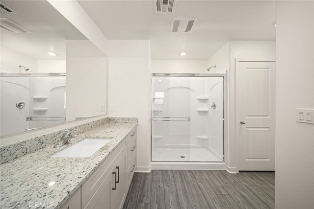 bathroom featuring hardwood / wood-style flooring, vanity, and an enclosed shower