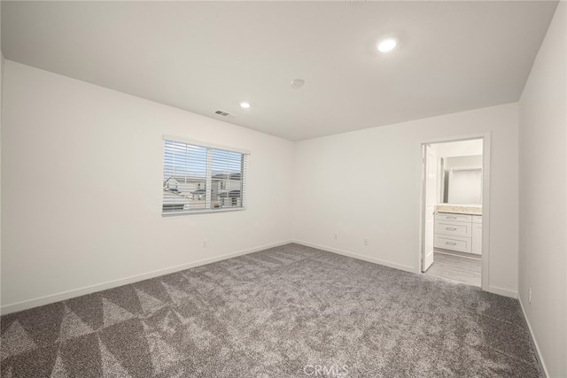 unfurnished bedroom featuring dark colored carpet and connected bathroom