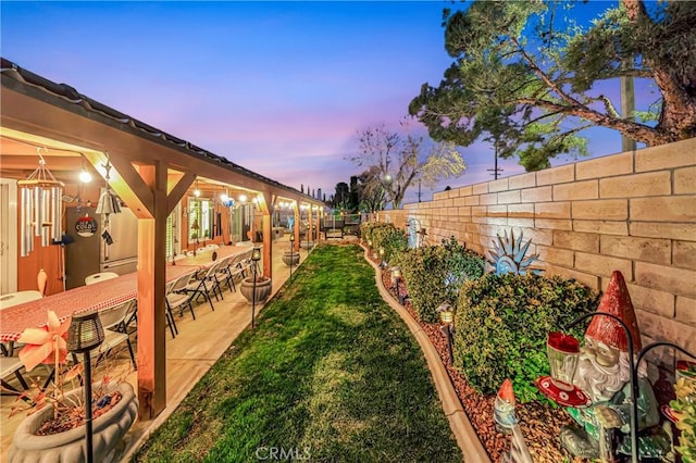 yard at dusk featuring a bar and a patio