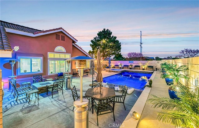 pool at dusk featuring a patio