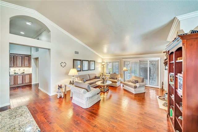 living room with vaulted ceiling, ornamental molding, and hardwood / wood-style floors