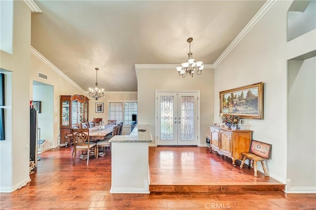 foyer featuring french doors, an inviting chandelier, ornamental molding, and hardwood / wood-style floors