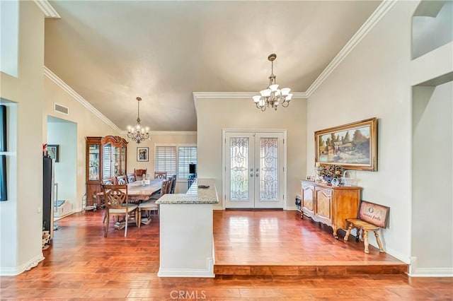 entrance foyer with hardwood / wood-style floors, a chandelier, crown molding, and french doors