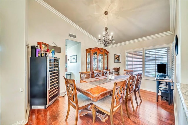 dining area featuring wine cooler, vaulted ceiling, a notable chandelier, and hardwood / wood-style flooring