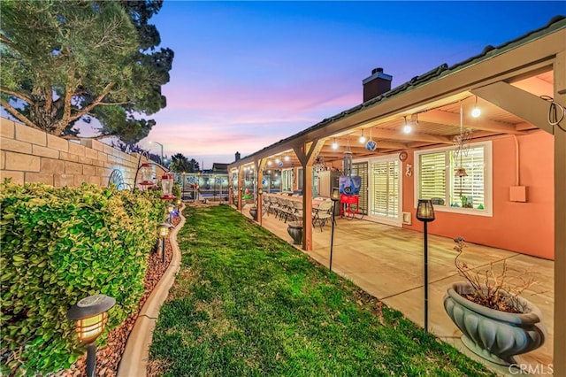 yard at dusk featuring a patio