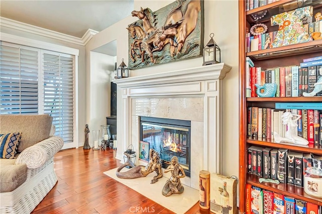 living area featuring ornamental molding, a fireplace, and hardwood / wood-style flooring