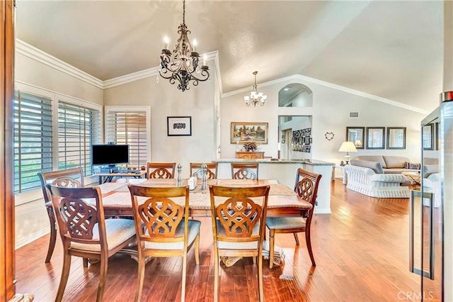 dining area with hardwood / wood-style floors, crown molding, lofted ceiling, and an inviting chandelier