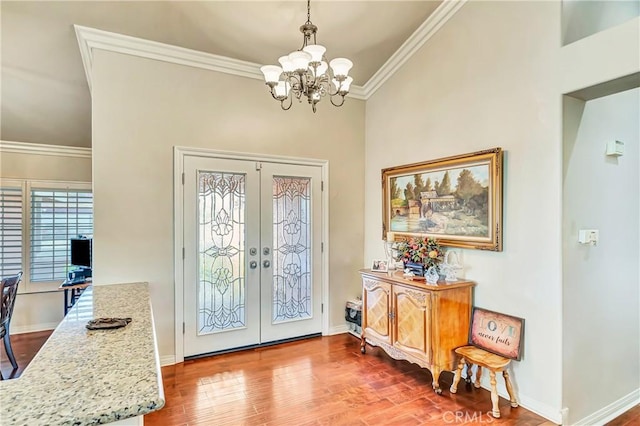 foyer entrance with hardwood / wood-style floors, a chandelier, crown molding, and french doors