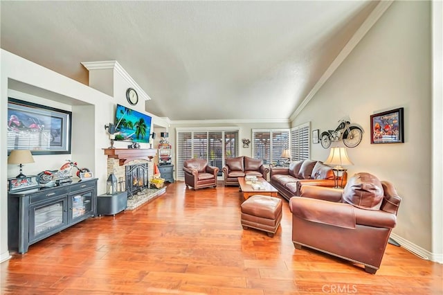 living room with vaulted ceiling, crown molding, a fireplace, and wood-type flooring