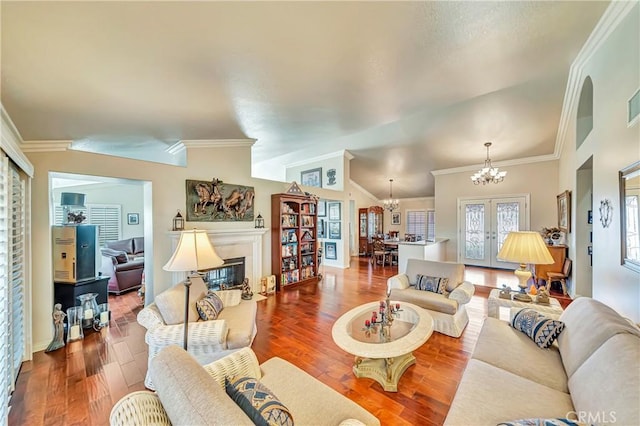 living room featuring vaulted ceiling, a notable chandelier, french doors, and hardwood / wood-style floors