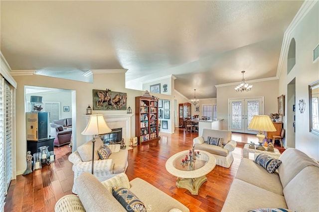 living room featuring hardwood / wood-style floors, lofted ceiling, french doors, a chandelier, and crown molding