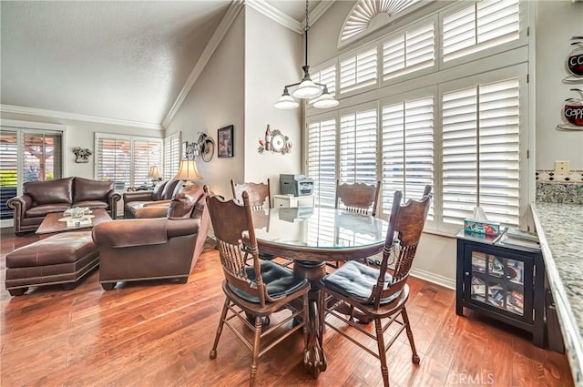 dining space with vaulted ceiling, a textured ceiling, crown molding, and wood-type flooring