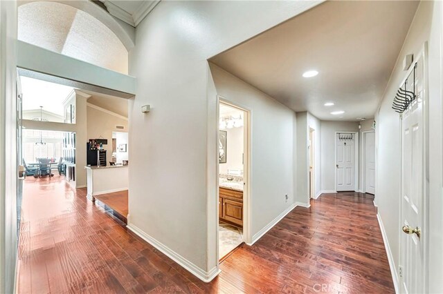 corridor with vaulted ceiling, dark hardwood / wood-style floors, and crown molding