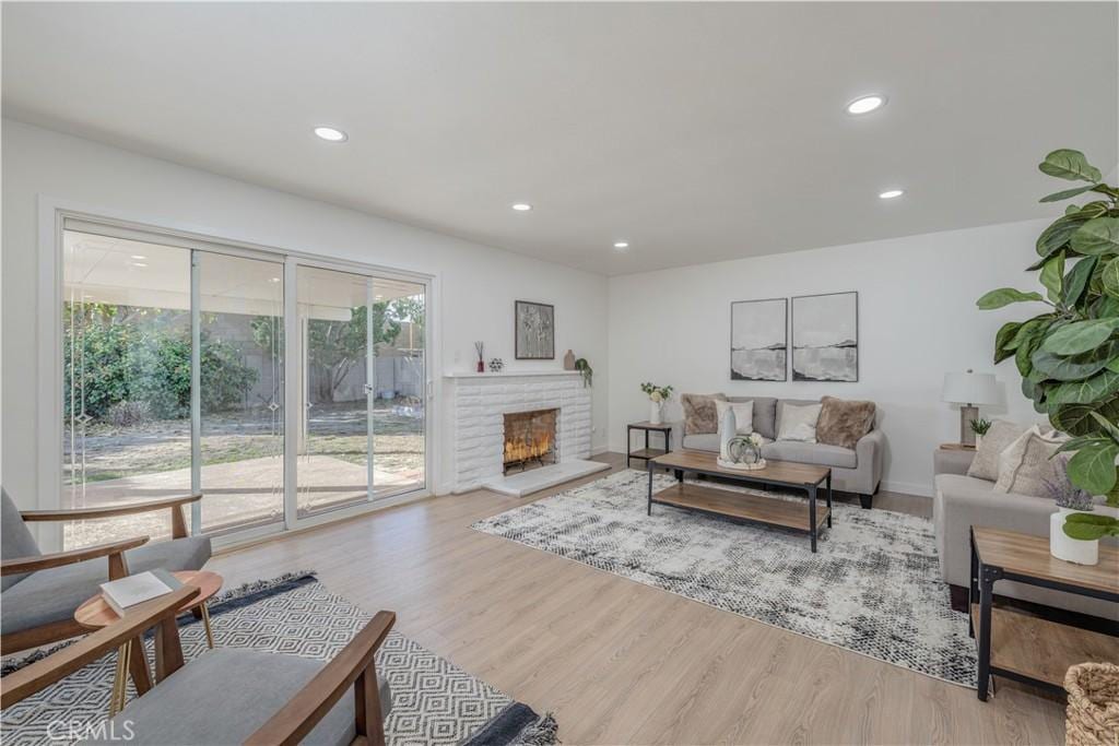 living area with baseboards, light wood finished floors, a fireplace, and recessed lighting